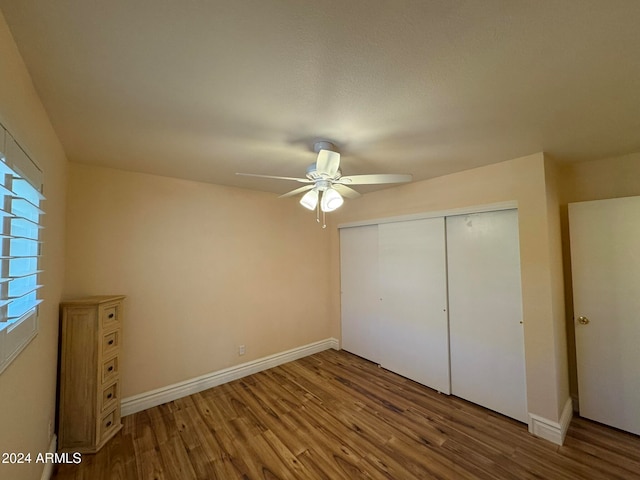 unfurnished bedroom featuring ceiling fan, a closet, and wood-type flooring