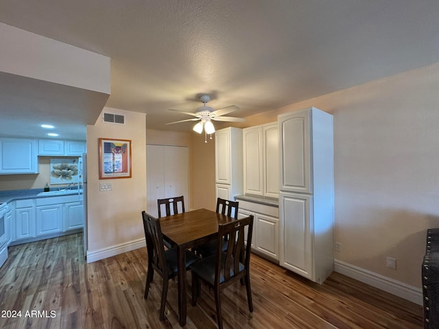 dining space with ceiling fan, dark wood-type flooring, and sink