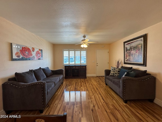 living room with a textured ceiling, ceiling fan, and hardwood / wood-style flooring