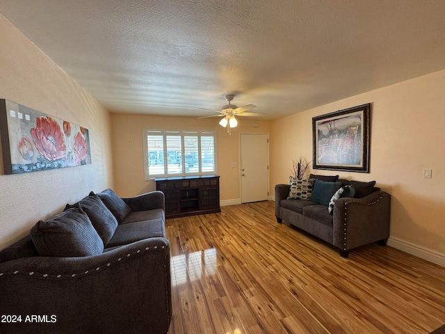 living room with a textured ceiling, ceiling fan, and light hardwood / wood-style flooring