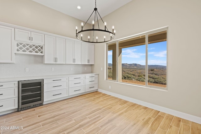 kitchen featuring a mountain view, backsplash, white cabinets, hanging light fixtures, and beverage cooler