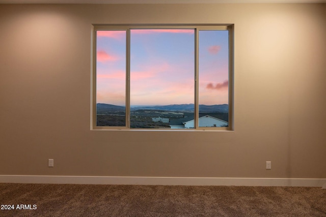 unfurnished room featuring a mountain view and carpet floors