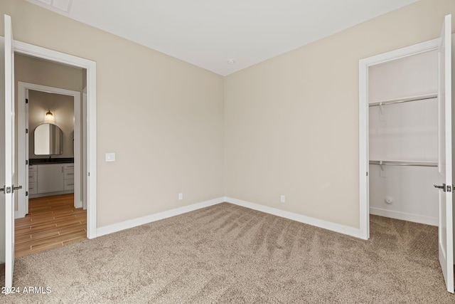 unfurnished bedroom featuring a walk in closet, light colored carpet, and a closet