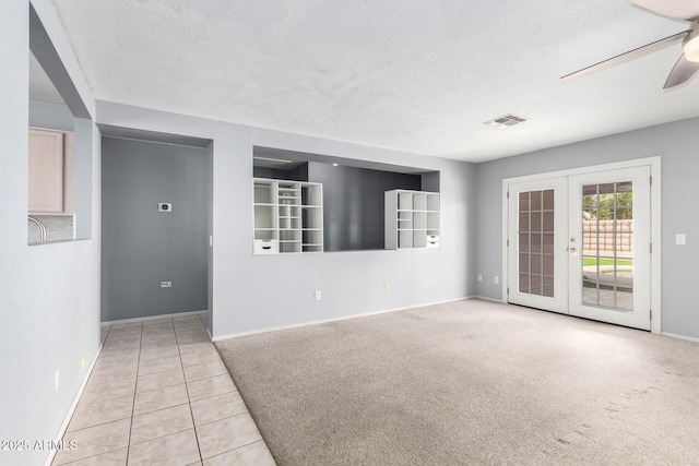 empty room with a textured ceiling, french doors, visible vents, and a ceiling fan