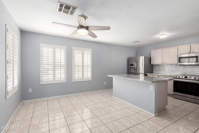 kitchen featuring visible vents, decorative backsplash, ceiling fan, a kitchen island, and appliances with stainless steel finishes