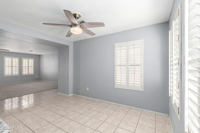 empty room featuring a ceiling fan, baseboards, and light tile patterned floors