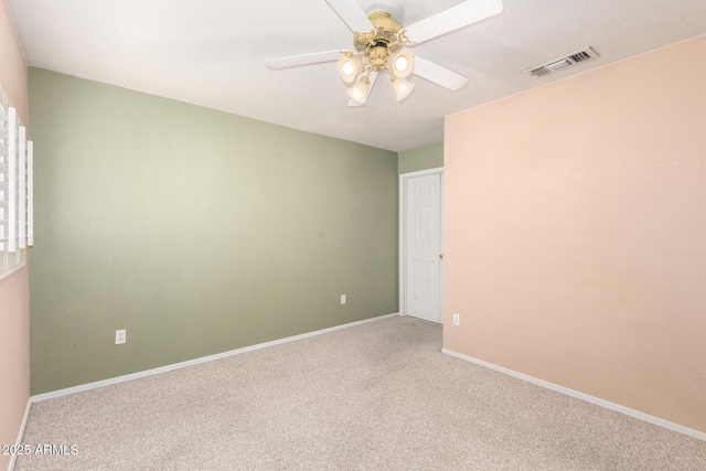 carpeted spare room featuring visible vents, ceiling fan, and baseboards