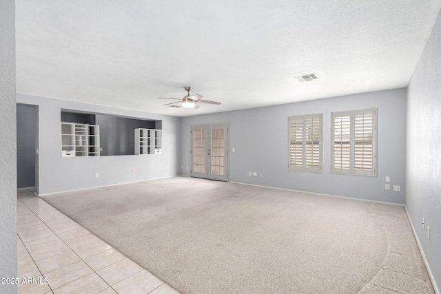 unfurnished room featuring baseboards, visible vents, light colored carpet, ceiling fan, and french doors