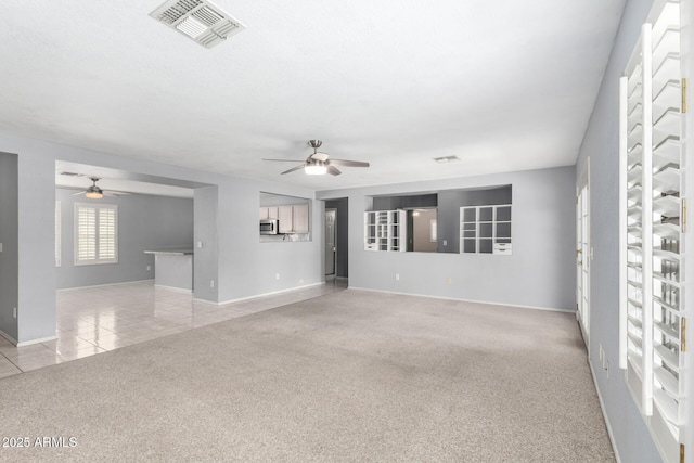 spare room with light tile patterned floors, light colored carpet, a ceiling fan, baseboards, and visible vents