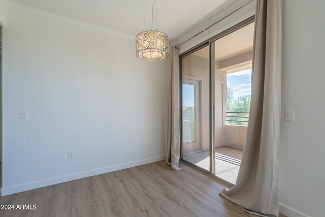 unfurnished room featuring a notable chandelier, ornamental molding, and light wood-type flooring