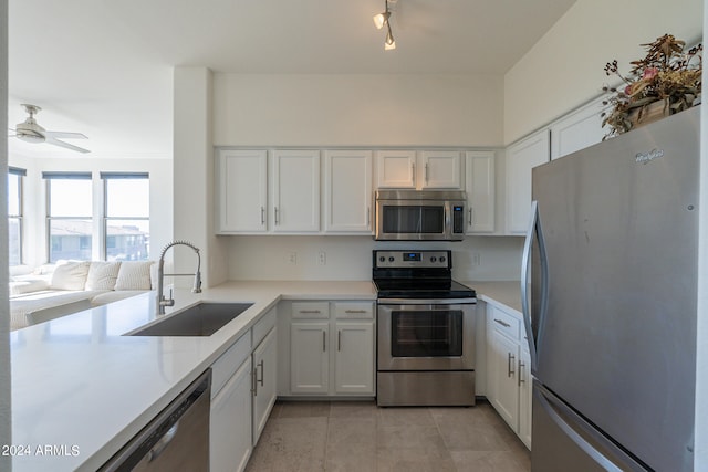 kitchen with ceiling fan, appliances with stainless steel finishes, sink, and white cabinets