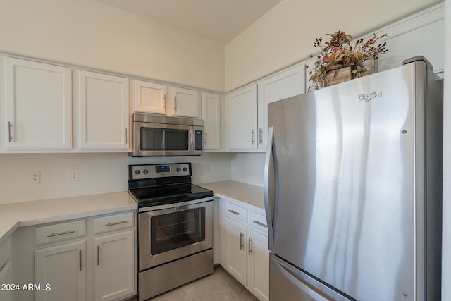 kitchen with appliances with stainless steel finishes, white cabinets, and light tile patterned floors