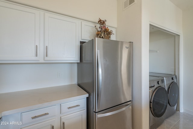 kitchen with light stone countertops, light tile patterned flooring, separate washer and dryer, stainless steel fridge, and white cabinetry