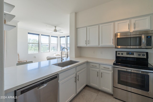 kitchen with appliances with stainless steel finishes, light tile patterned flooring, white cabinets, and sink