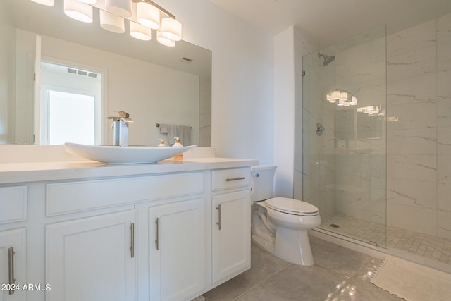 bathroom with vanity, tiled shower, toilet, and tile patterned flooring