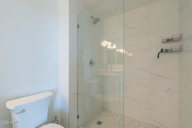 bathroom with a tile shower and toilet