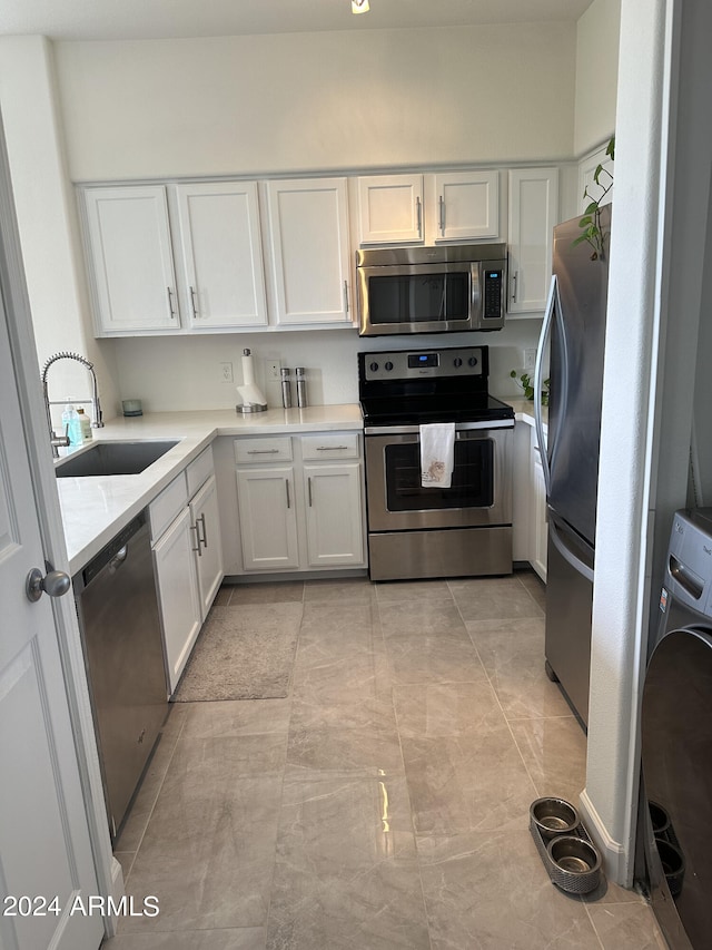 kitchen with appliances with stainless steel finishes, sink, and white cabinets