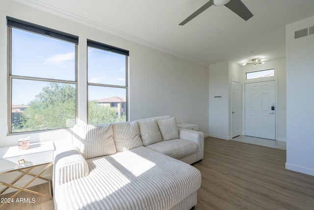 living room with ceiling fan, wood-type flooring, a wealth of natural light, and ornamental molding