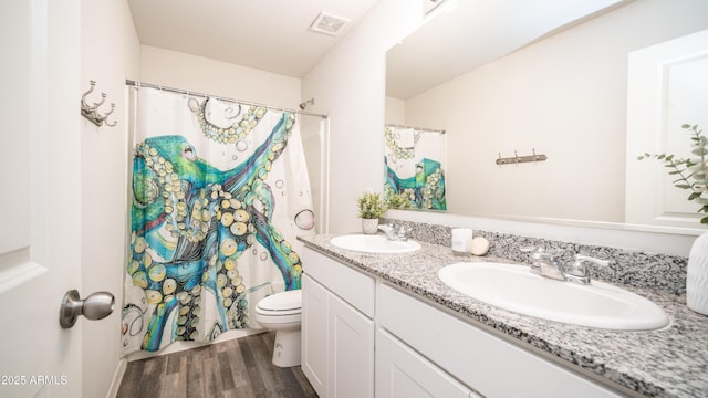 bathroom with double vanity, visible vents, a sink, and wood finished floors