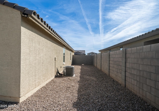 view of property exterior featuring central AC unit, a fenced backyard, and stucco siding