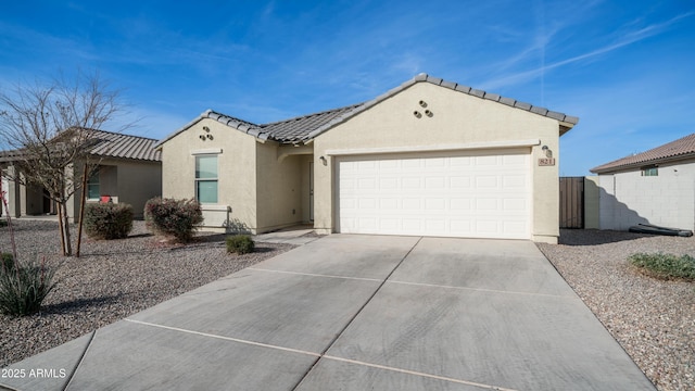 view of front facade with an attached garage, a tiled roof, concrete driveway, and stucco siding