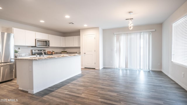 kitchen with stainless steel appliances, visible vents, dark wood-type flooring, a kitchen island with sink, and white cabinetry