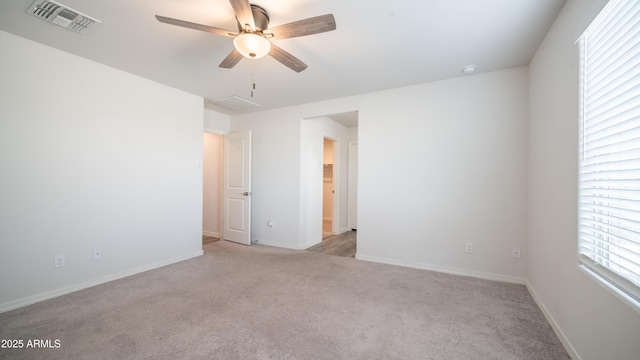 spare room with a ceiling fan, visible vents, light carpet, and baseboards