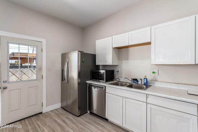 kitchen featuring sink, appliances with stainless steel finishes, light hardwood / wood-style flooring, and white cabinetry