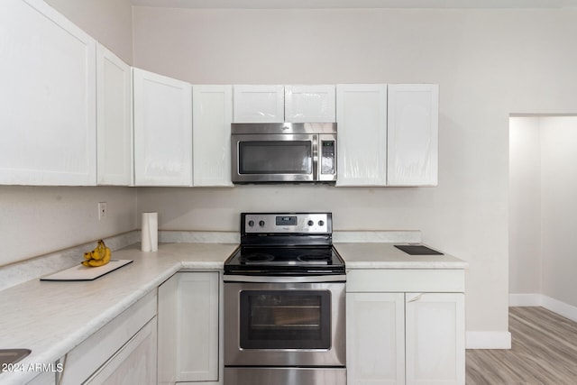 kitchen with light hardwood / wood-style flooring, white cabinetry, and stainless steel appliances