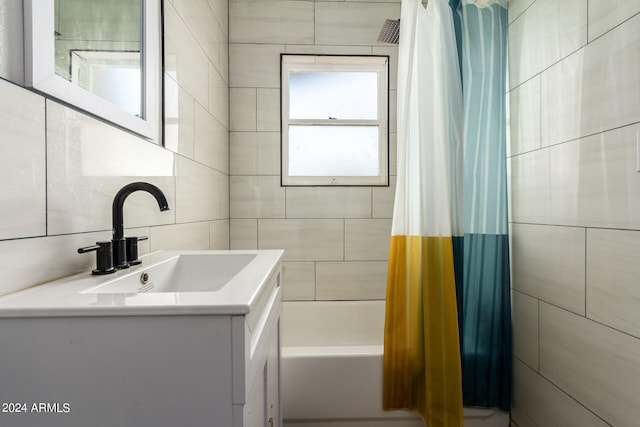 bathroom with shower / bath combo with shower curtain, vanity, backsplash, and tile walls