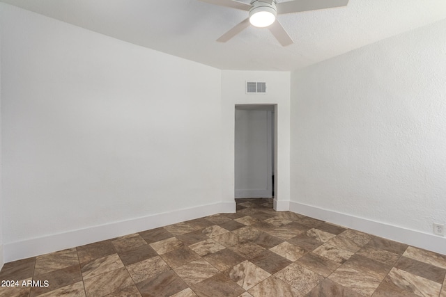 spare room featuring ceiling fan and dark tile patterned flooring