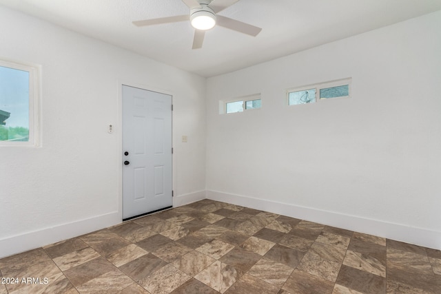 unfurnished room featuring dark tile patterned floors, a healthy amount of sunlight, and ceiling fan