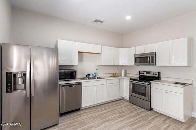 kitchen featuring sink, light hardwood / wood-style flooring, white cabinetry, and stainless steel appliances