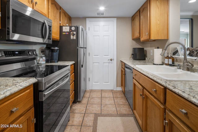 kitchen with sink, light tile patterned floors, light stone counters, and appliances with stainless steel finishes