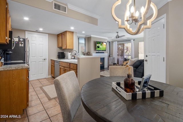 dining area with ceiling fan with notable chandelier, light tile patterned flooring, ornamental molding, and sink