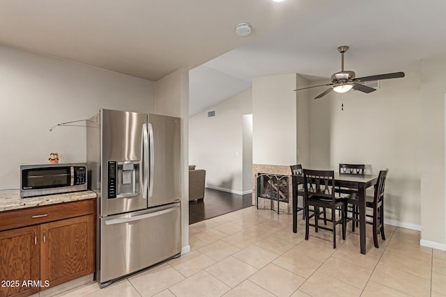 332 S 83rd Pl, Mesa, AZ 85208 - kitchen with stainless steel appliances, light tile patterned floors, ceiling fan, vaulted ceiling, and brown cabinetry
