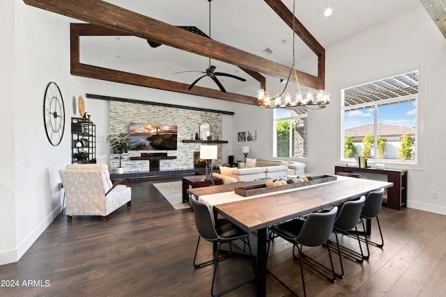 dining space with ceiling fan with notable chandelier, a wealth of natural light, dark wood-type flooring, and a fireplace