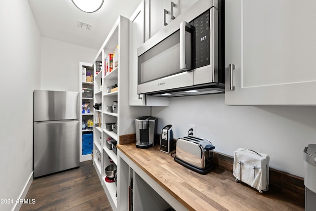 kitchen with butcher block countertops, dark hardwood / wood-style flooring, and stainless steel appliances