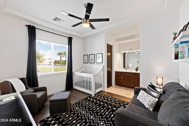 bedroom featuring ceiling fan, a tray ceiling, connected bathroom, and wood-type flooring