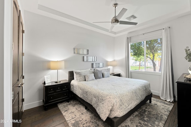 bedroom featuring a tray ceiling, ceiling fan, and dark wood-type flooring