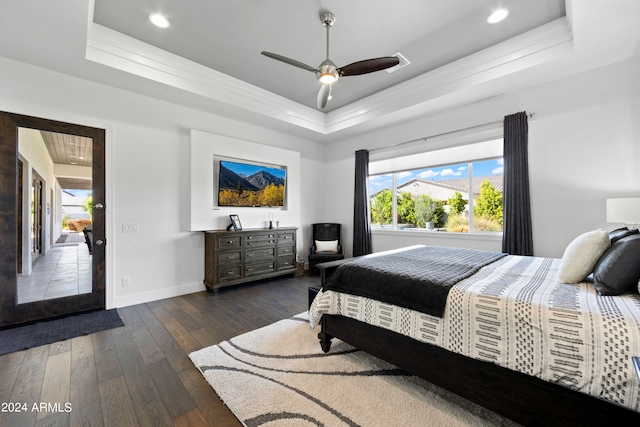 bedroom featuring a tray ceiling, dark hardwood / wood-style floors, and ceiling fan