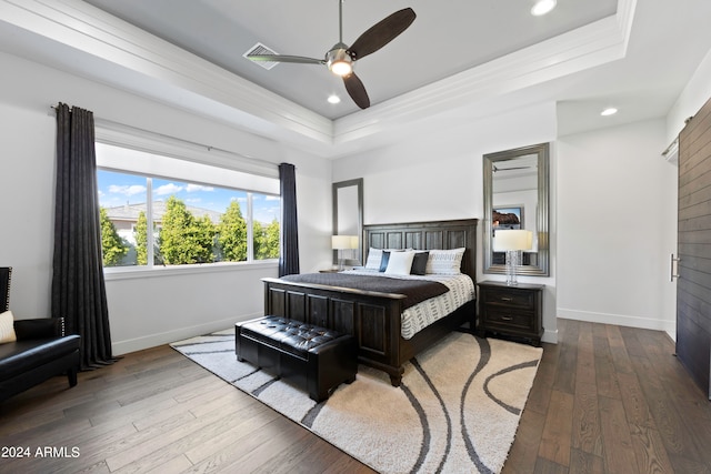 bedroom featuring ceiling fan, hardwood / wood-style flooring, and a tray ceiling