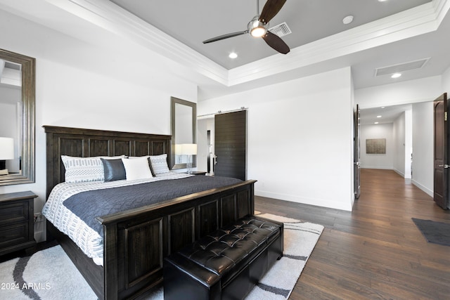 bedroom featuring ceiling fan, a raised ceiling, dark hardwood / wood-style floors, and a barn door