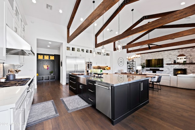 kitchen with a large island with sink, a fireplace, white cabinets, and high vaulted ceiling