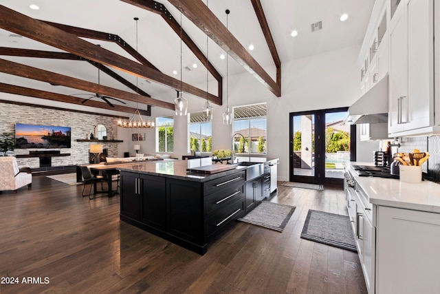 kitchen featuring a kitchen island with sink, white cabinetry, dark hardwood / wood-style floors, and pendant lighting