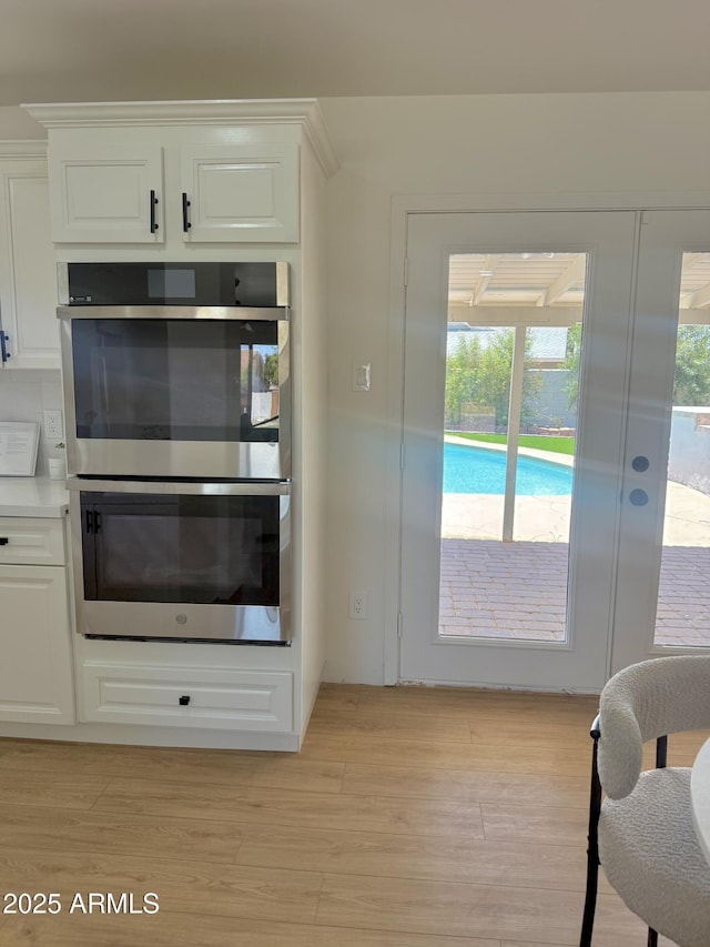 1421 W Pasadena Ave, Phoenix, AZ 85013 - kitchen with double oven, white cabinets, light wood-type flooring, and light countertops