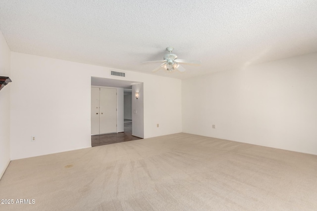 carpeted spare room with visible vents, ceiling fan, and a textured ceiling