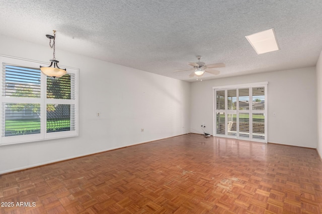 spare room featuring a skylight, baseboards, a ceiling fan, and a textured ceiling