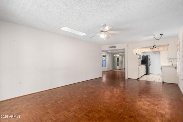 unfurnished room featuring a sink, ceiling fan, visible vents, and a textured ceiling