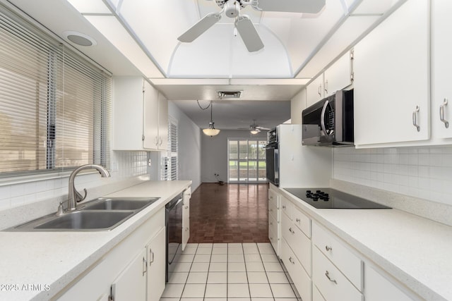 kitchen featuring light tile patterned floors, dishwashing machine, black electric stovetop, oven, and a sink